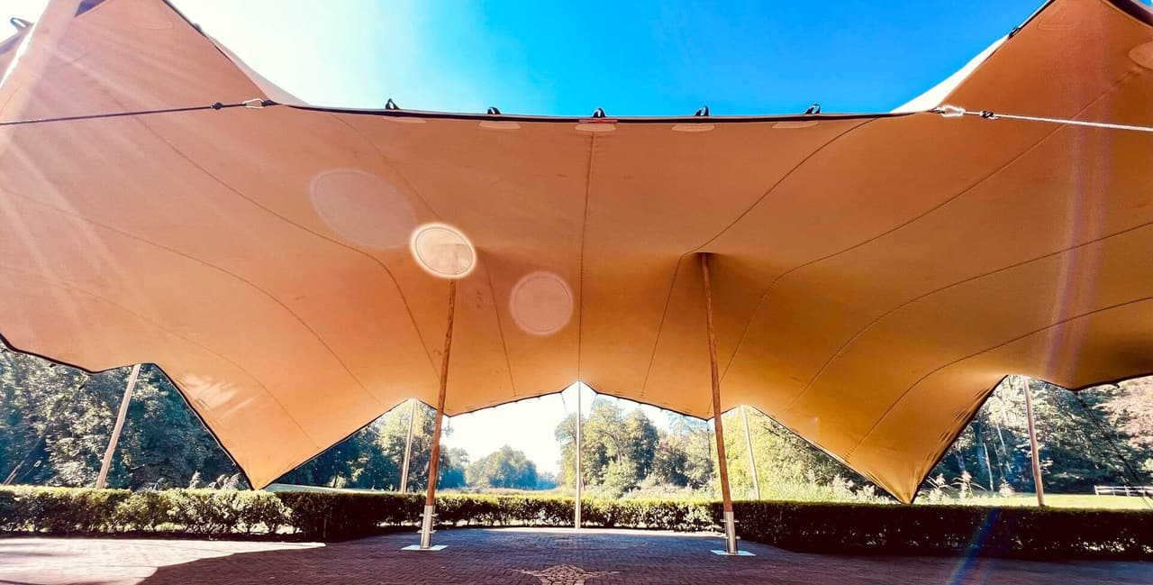 Tent huren voor een evenement met bezoekers onder een verlichte stretchtent
